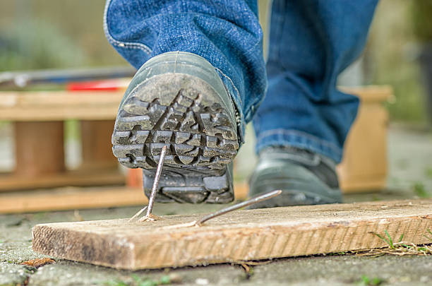 Worker in safety boots about to step on a nail Worker with safety boots steps on a nail toenail stock pictures, royalty-free photos & images