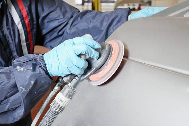 Worker in safety gear using a machine to polish a surface stock photo