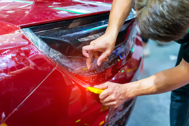 Worker install car paint protection film with spatula stock photo
