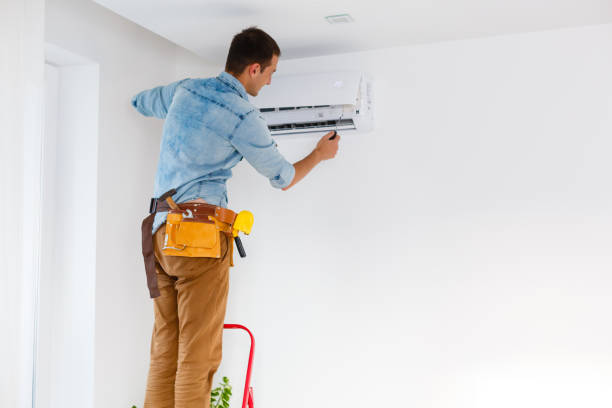 Worker installs grid on the air conditioner in the new apartment stock photo