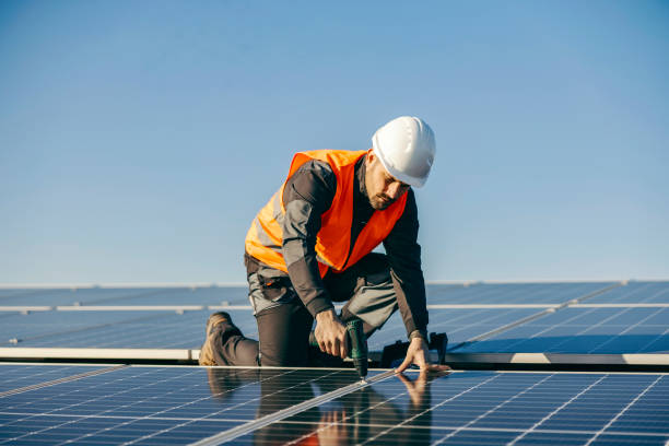Worker installs solar panels on rooftop. stock photo