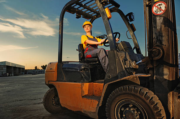 A worker operating a forklift at dusk stock photo