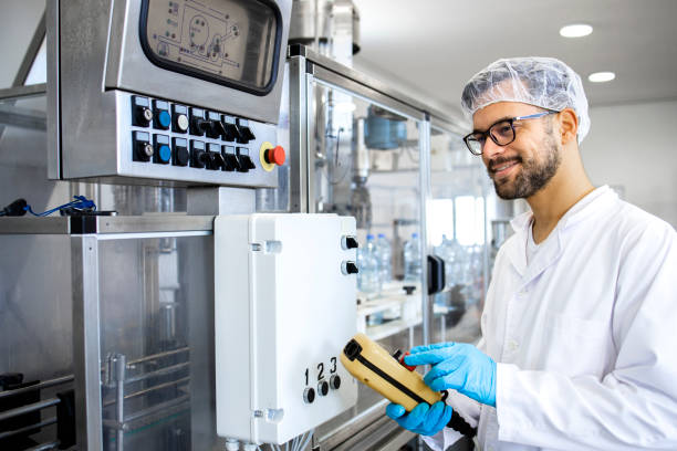 Worker or technologist operating industrial production machine in food processing factory. Worker or technologist operating industrial production machine in food processing factory. food industry cleaning stock pictures, royalty-free photos & images