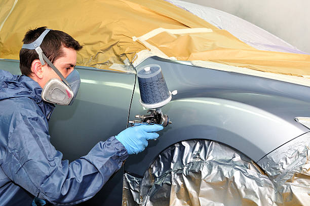 worker painting a car. - bumper stockfoto's en -beelden