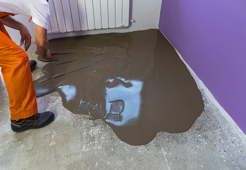 Worker Puts A Self Leveling Screed With Tool On Concrete Floor In