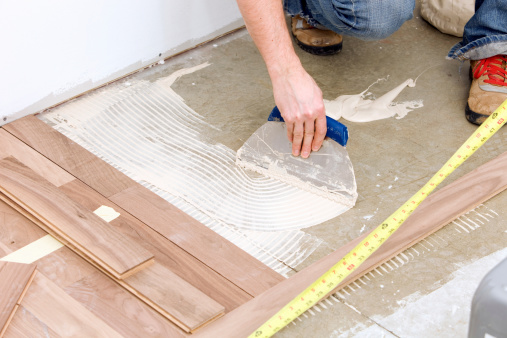 Worker Troweling Adhesive For A Hardwood Over Concrete Floor Stock