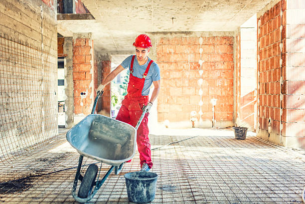 worker with empty wheelbarrow on construction site worker with empty wheelbarrow on construction site bricklayer stock pictures, royalty-free photos & images