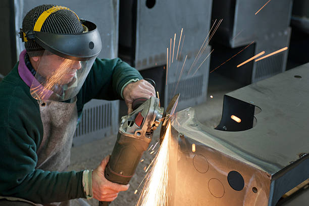 Worker with face shield makes a soldering, producing sparks stock photo