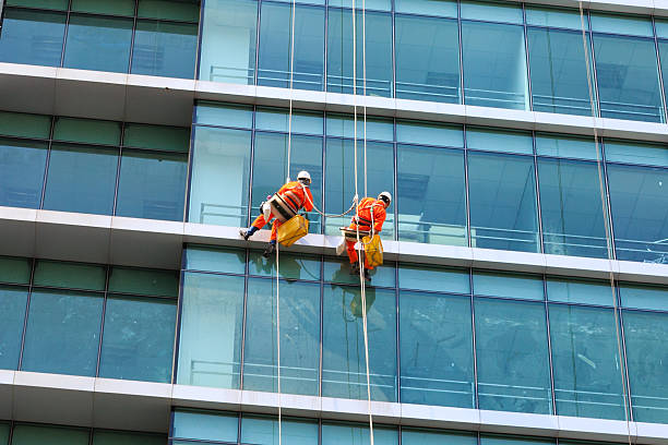 Workers clean the glass on tall buildings stock photo