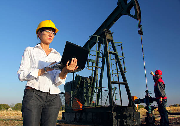 Workers in an Oilfield, teamwork Female engineer with notebook and oil man working together in an oilfield, teamwork oil field stock pictures, royalty-free photos & images