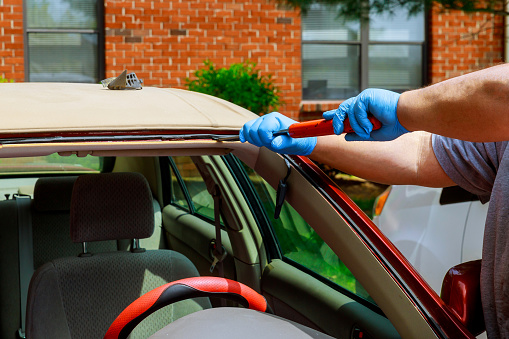 Workers removing glazing windshield on a car of a car service