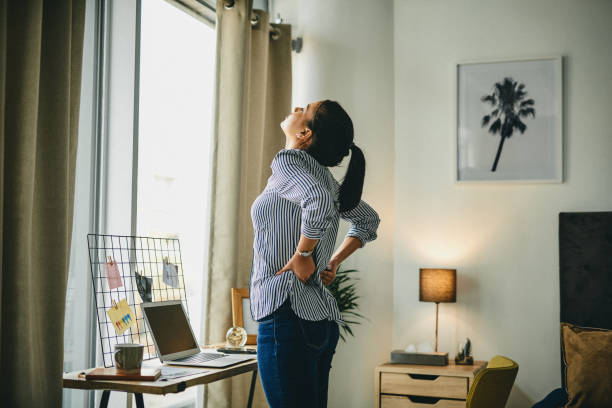 Working at home can be a real pain in the back Rearview shot of a young woman suffering with back pain while working from home back pain stock pictures, royalty-free photos & images