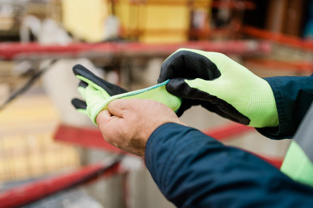 Workman at construction site putting on gloves. stock photo