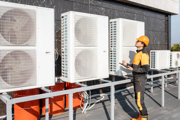 Workman servicing air conditioning or heat pump with digital tablet Professional workman in protective clothing adjusting the outdoor unit of the air conditioner or heat pump with digital tablet air conditioner stock pictures, royalty-free photos & images