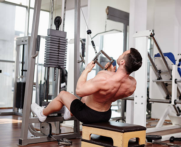 Workout at cable machine Man lifting weights at the cable machine in a gym tricep curl machine stock pictures, royalty-free photos & images