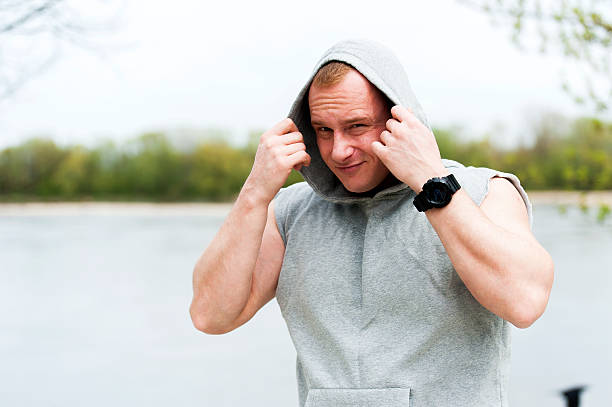 Workout man in hood resting by the river outdoor. stock photo