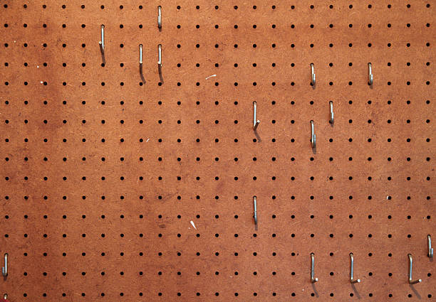 Workshop pegboard Empty pegboard with hooks for hanging tools in a woodworking shop . pegboard stock pictures, royalty-free photos & images