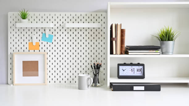 Workspace pegboard and shelves with office supplies on white office desk. Workspace pegboard and shelves with office supplies on white office desk. pegboard stock pictures, royalty-free photos & images