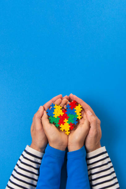 World autism awareness day concept. Adult and child hands holding puzzle heart on light blue background World autism awareness day concept. Adult and kid hands holding puzzle heart on light blue background autism stock pictures, royalty-free photos & images