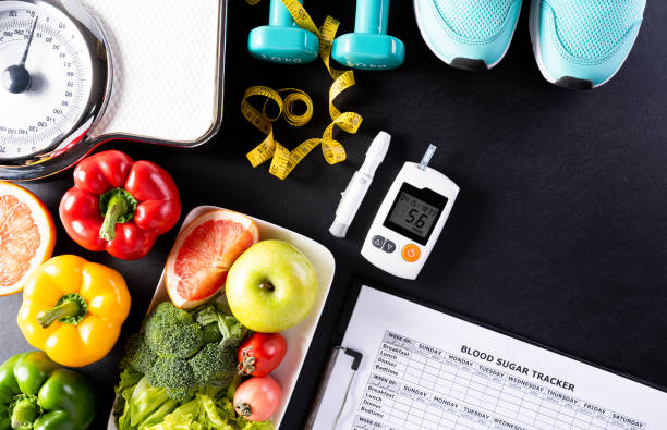 World diabetes day, Healthcare and medical concept. Healthy food including fresh fruits, vegetables, weight scale, sports shoes, dumbells, measure tape and diabetic measurement set on black background. stock photo