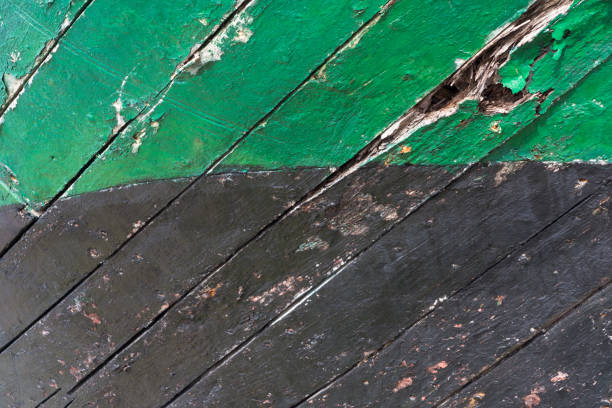 Worn and cracked timber on a small wooden boats keel. Green and black peeling paint. stock photo