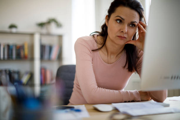 Worried businesswoman looking at computer screen Worried businesswoman looking at computer screen wasting time stock pictures, royalty-free photos & images