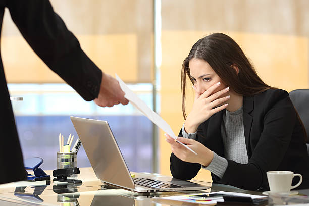 Worried businesswoman receiving notification Worried businesswoman receiving a notification from a colleague in her workplace at office being fired photos stock pictures, royalty-free photos & images