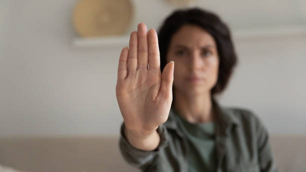 Worried concerned young woman showing palm, making hand stop gesture stock photo