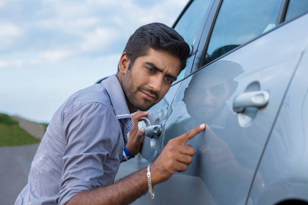 worried funny looking man obsessing about cleanliness of his car Young worried funny looking man obsessing about cleanliness of his new car. Car care and protection concept dented stock pictures, royalty-free photos & images