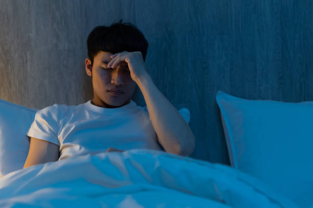 worried man on bed close up of asian young man is worrying about something on bed at night insomnia stock pictures, royalty-free photos & images