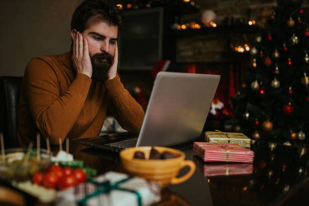 Worried man using laptop and working for Christmas stock photo