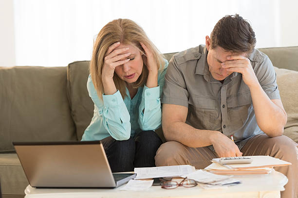 Worried mature couple calculating home finances on sofa stock photo