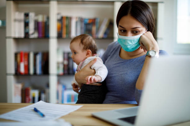 worried mother with face protective mask working from home - pandemia doença imagens e fotografias de stock