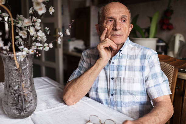 Worried senior man looking in distance Old man sitting at a table with serious face expression dementia stock pictures, royalty-free photos & images