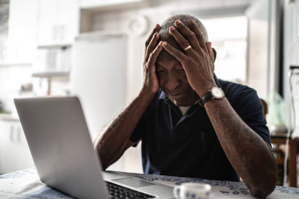 Worried senior man working at laptop Worried senior man working at laptop sad old black man stock pictures, royalty-free photos & images