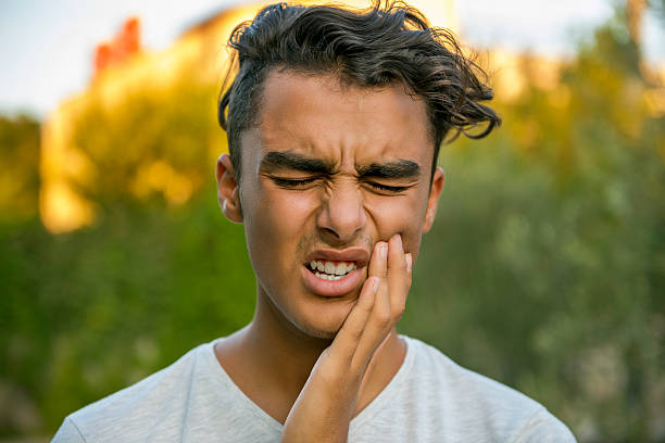 Worried teenage boy rubbing his mouth because of toothache stock photo