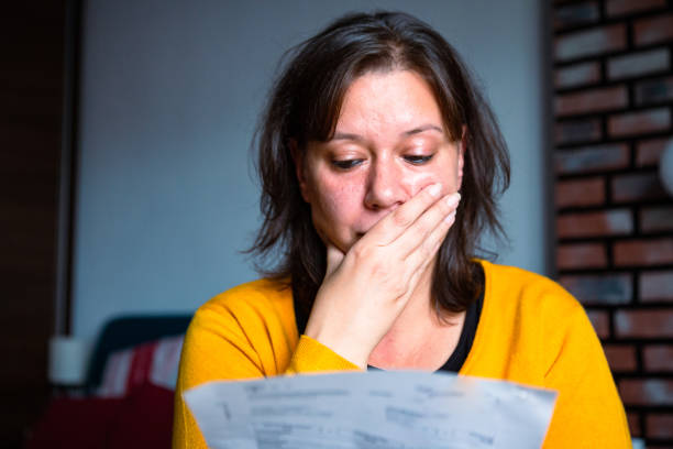 Worried woman checking bills at home stock photo