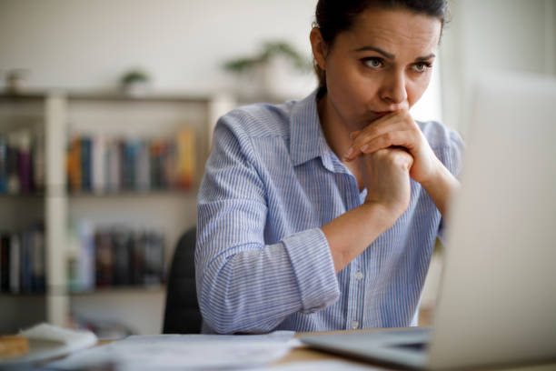 Worried woman looking at computer screen Worried woman looking at computer screen physical pressure photos stock pictures, royalty-free photos & images
