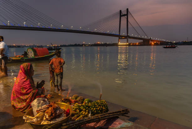 Worship April 11,2019. Kolkata, India. An Unidentified Indian Bihari woman with Puja Thali, worship River Ganges at Prinsep Ghat, overlooking Vidyasagar Setu/ Second Hooghly Bridge. chhath stock pictures, royalty-free photos & images