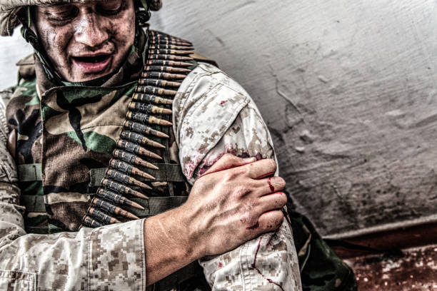 Wounded in shoulder soldier trying stop bleeding stock photo