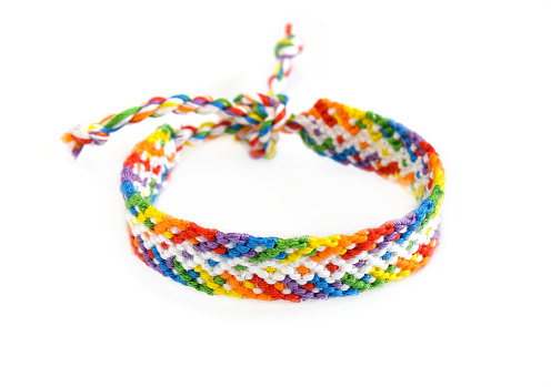 Woven DIY friendship bracelet handmade of embroidery bright thread with knots isolated on white background.