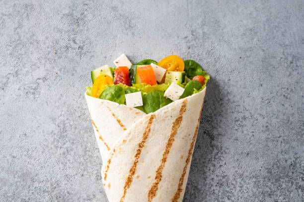 Wrap sandwich, roll with fish salmon, vegetables and cheese. Grey background. Top view. stock photo