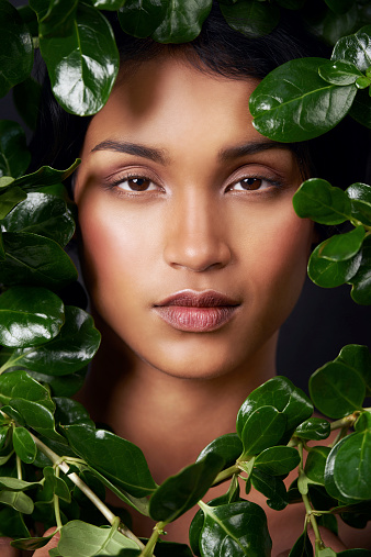 Studio shot of an attractive young ethnic woman surrounded by leaves