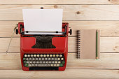istock Writer or journalist workplace - vintage red typewriter on the wooden desk 1351107338