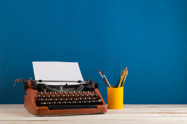 writer's workplace - red typewriter and stationery on blue blackboard background stock photo