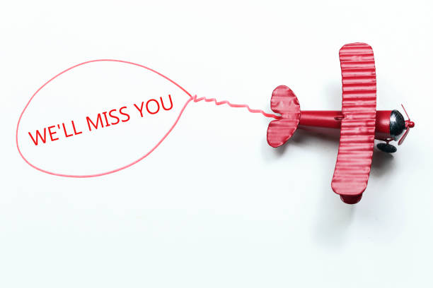 writing We'll Miss You red toy airplane with talk bubble on white background stock photo