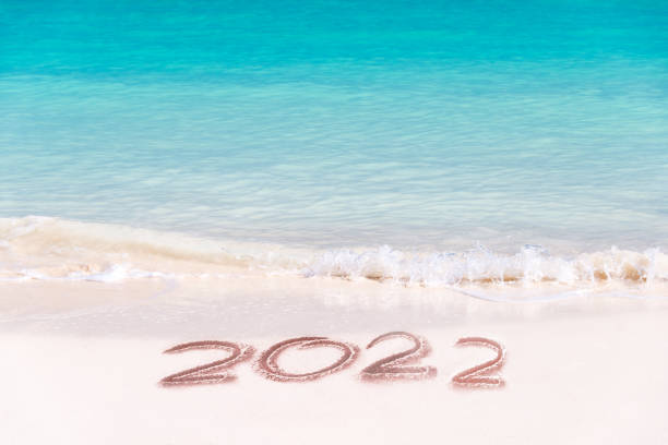 2022 written on the sand of a tropical beach, travel new year card stock photo