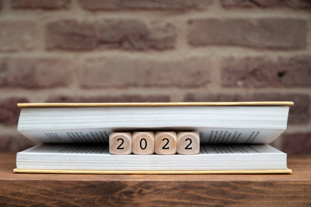 2022 written on wooden blocks between book pages on a shelf. stock photo
