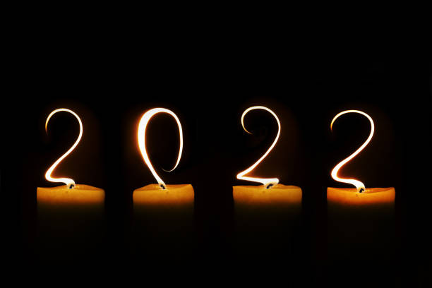 2022 written with candle flames on black background, new year greeting card stock photo