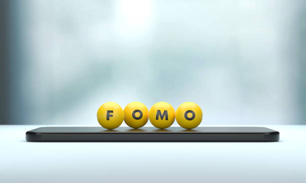 FOMO Written Yellow Spheres Sitting On Mobile Phone. FOMO Written Yellow Spheres Sitting On Mobile Phone. Social Media Terms and Communication Concept. fomo photos stock pictures, royalty-free photos & images